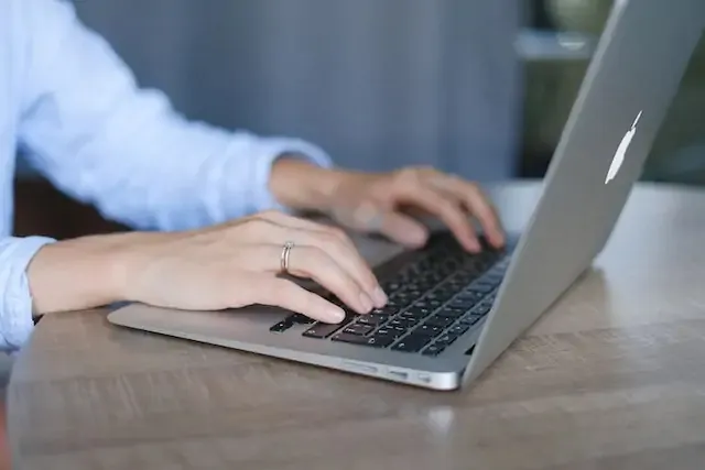 person-in-blue-shirt-writing-on-their-laptop-at-a-desk