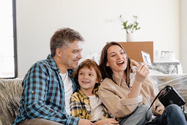 happy-family-sitting-on-a-couch-smiling-and-looking-at-a-photograph-together happy-family-sitting-on-a-couch-smiling-and-looking-at-a-photograph-together